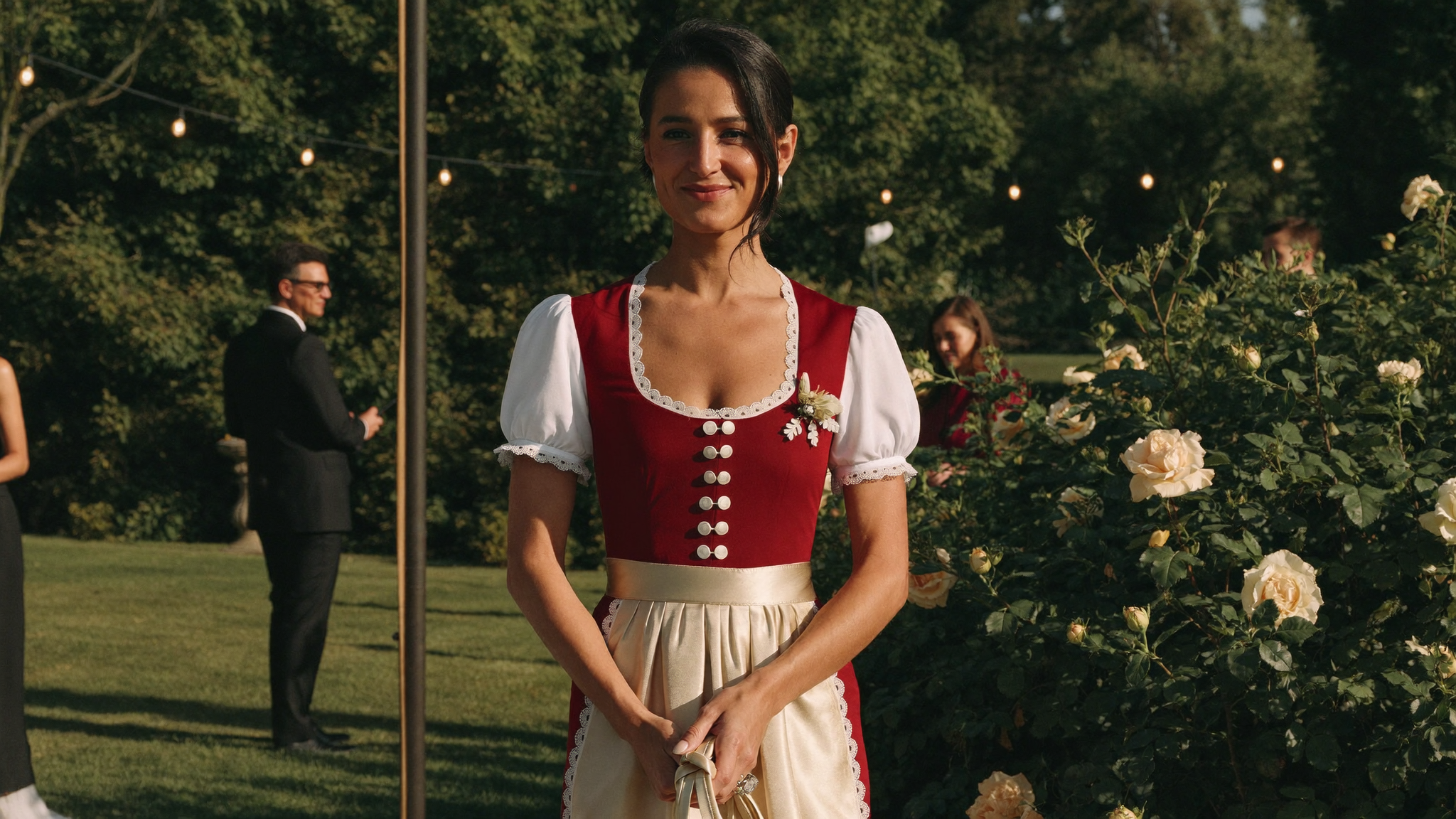 Dirndl als Hochzeitsgast: elegante Gaestin im weinroten Dirndl im Hochzeitsgarten